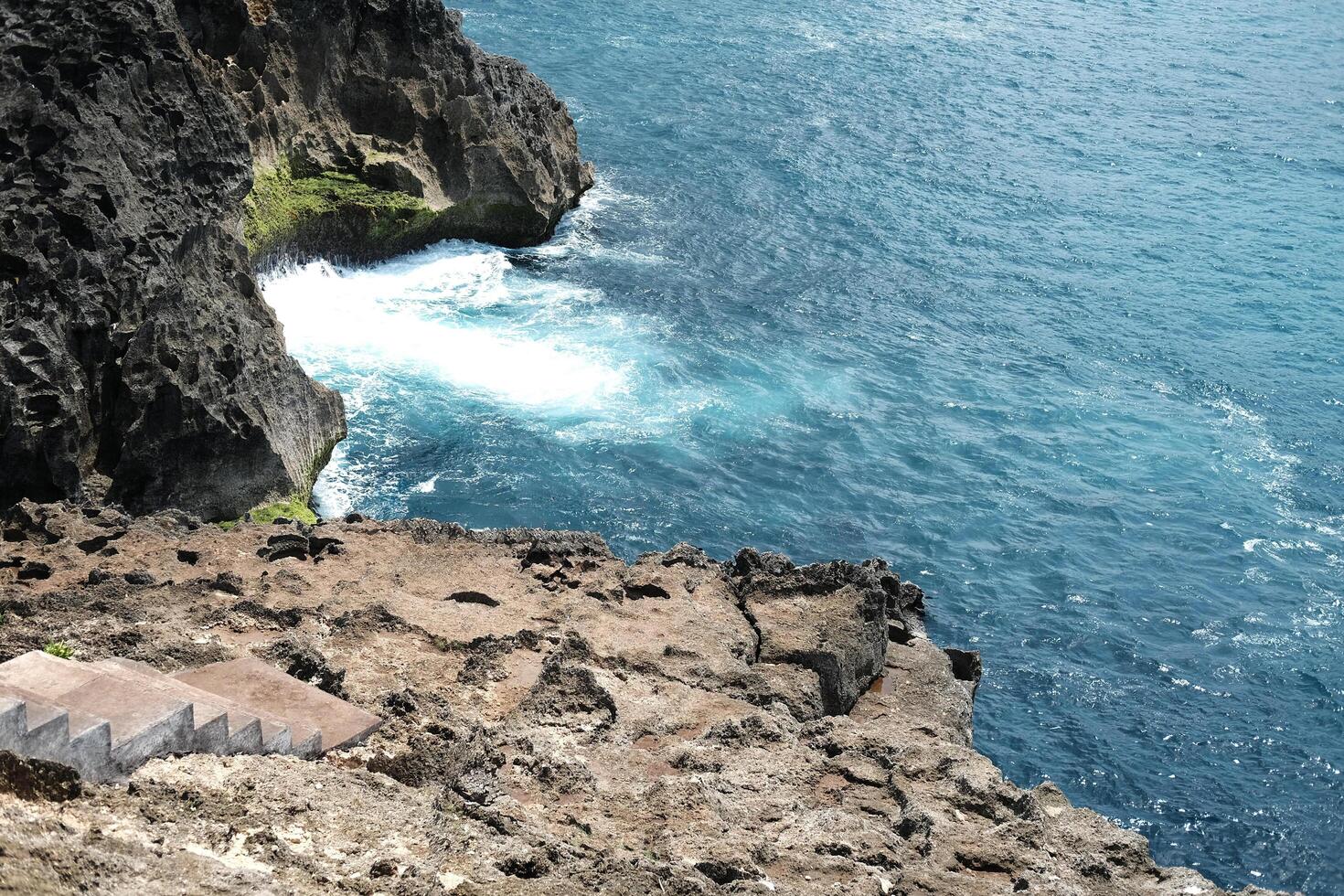 Landscape aerial view of cave in rocky cliff at the sea with foam waves and splash water. Travel destination seascape of summer calm ocean in Bali at Indonesia photo