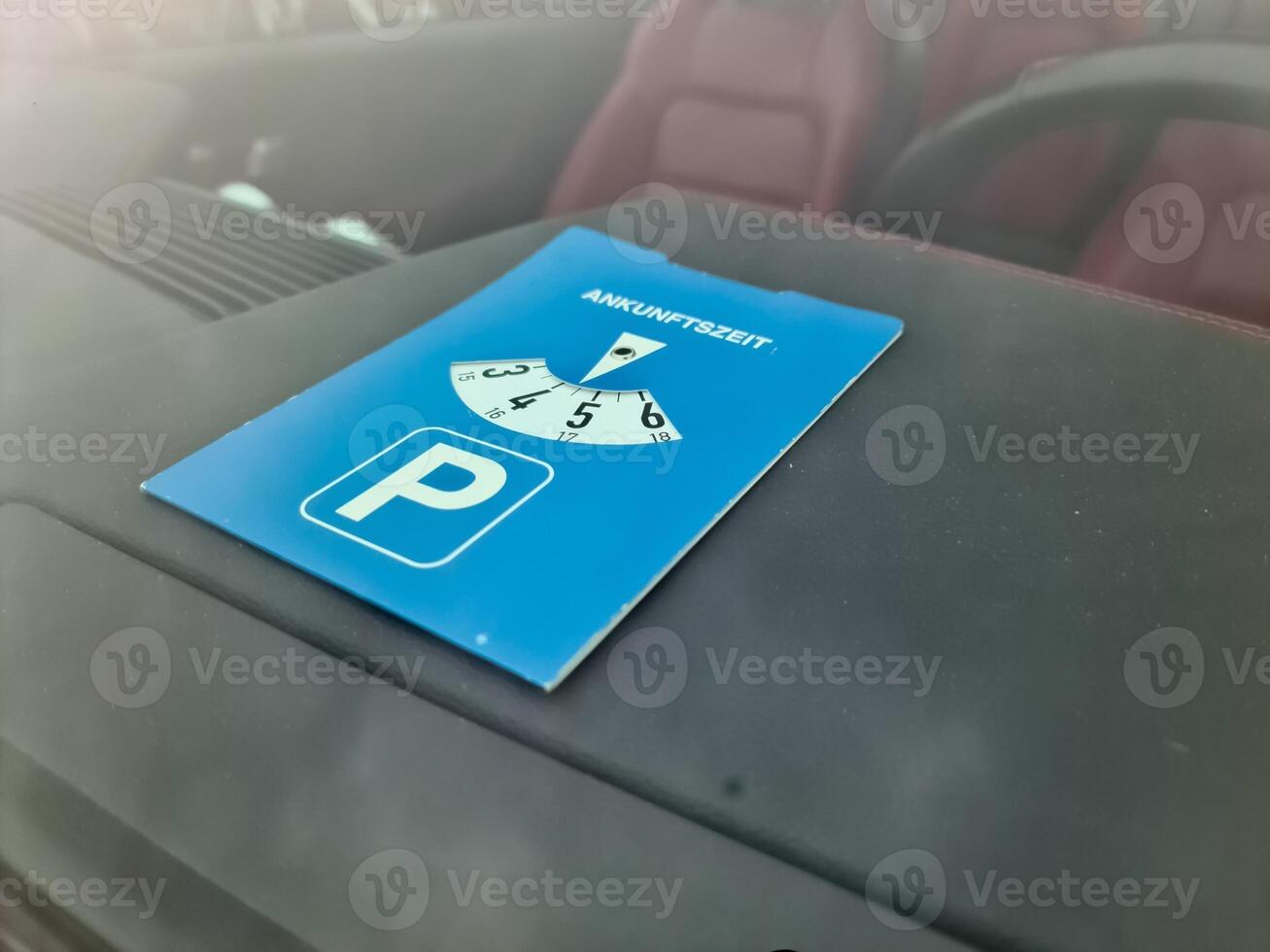 Blue parking disc showing arrival time inside car windshield photo