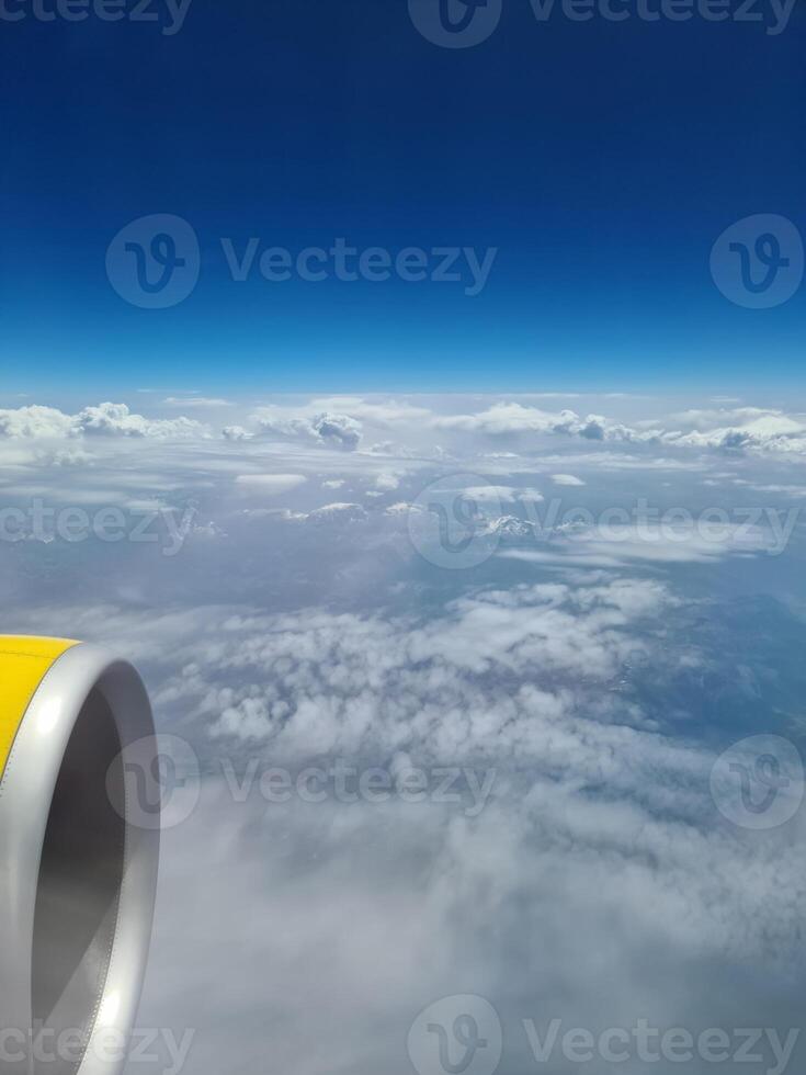 Airplane engine flying above the clouds with blue sky photo