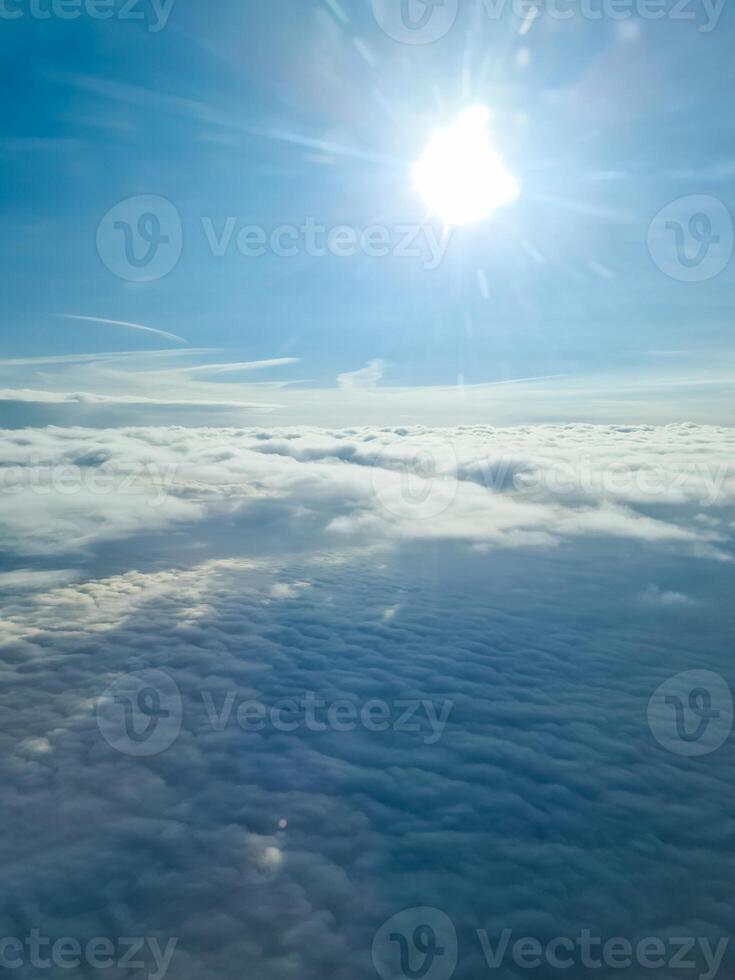 The sun shining over a sea of clouds from airplane window photo
