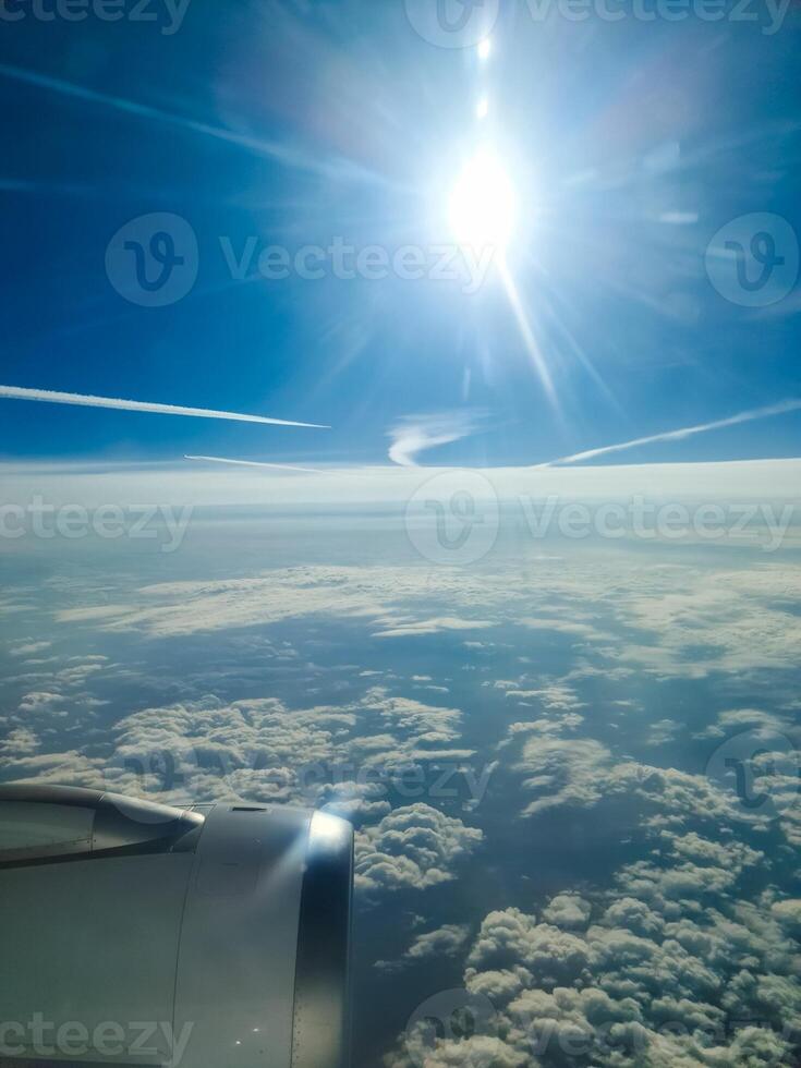 An Airplane engine flying above the clouds during a sunny day photo