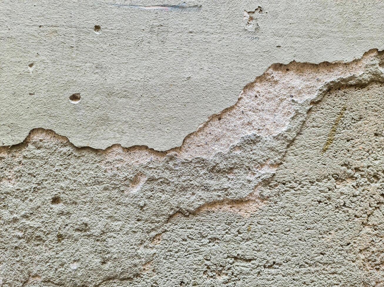Old damaged plaster wall with holes and cracks showing underlying layer photo