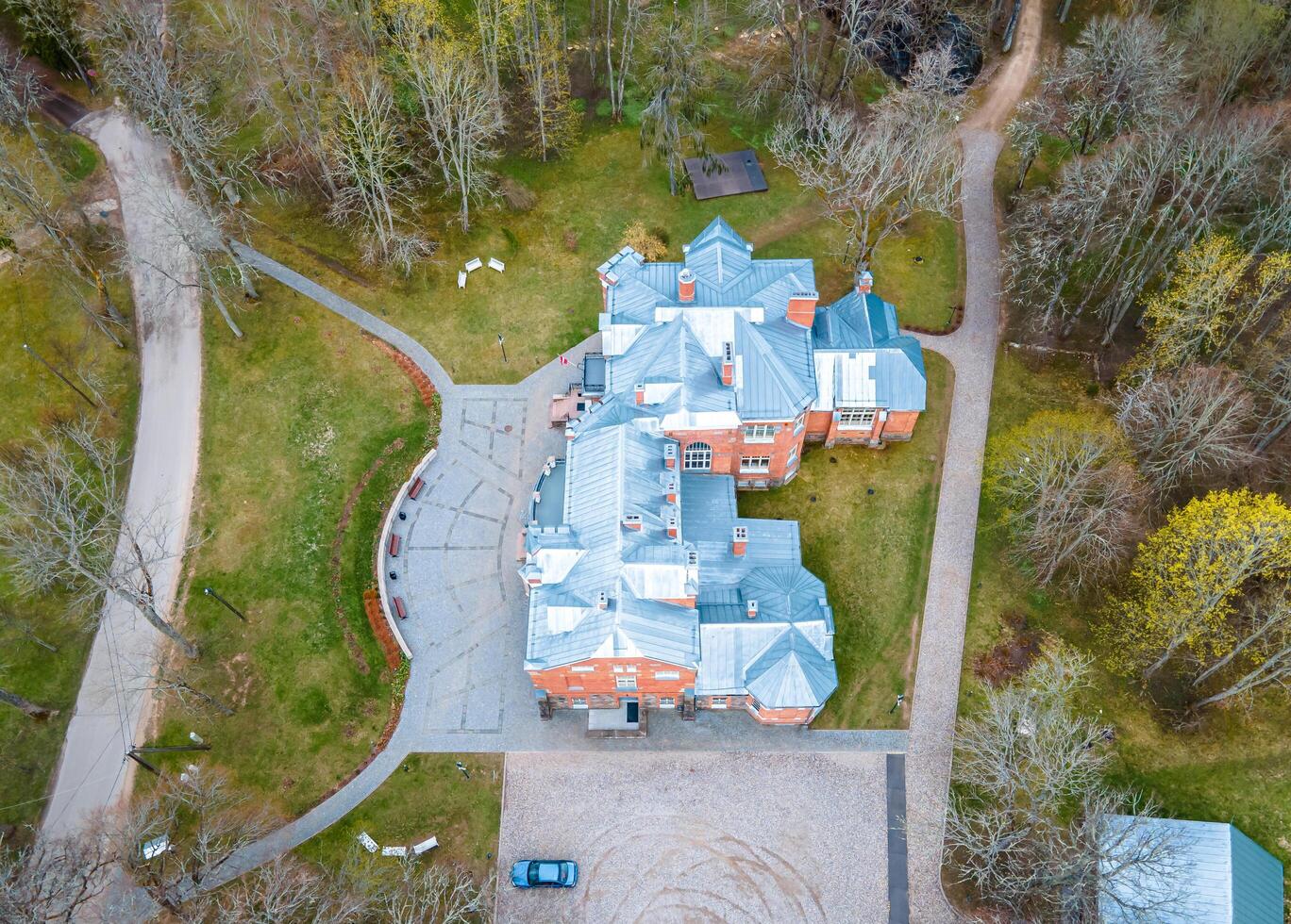 Riga, Latvia, 2024 - Aerial View of Historic Brick Building in Wooded Area During Spring photo