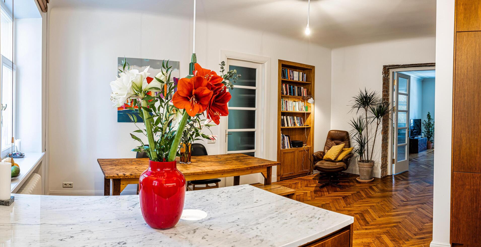 Riga, Latvia, 2024 - Modern Kitchen and Dining Area with Vibrant Red Vase and Flowers photo