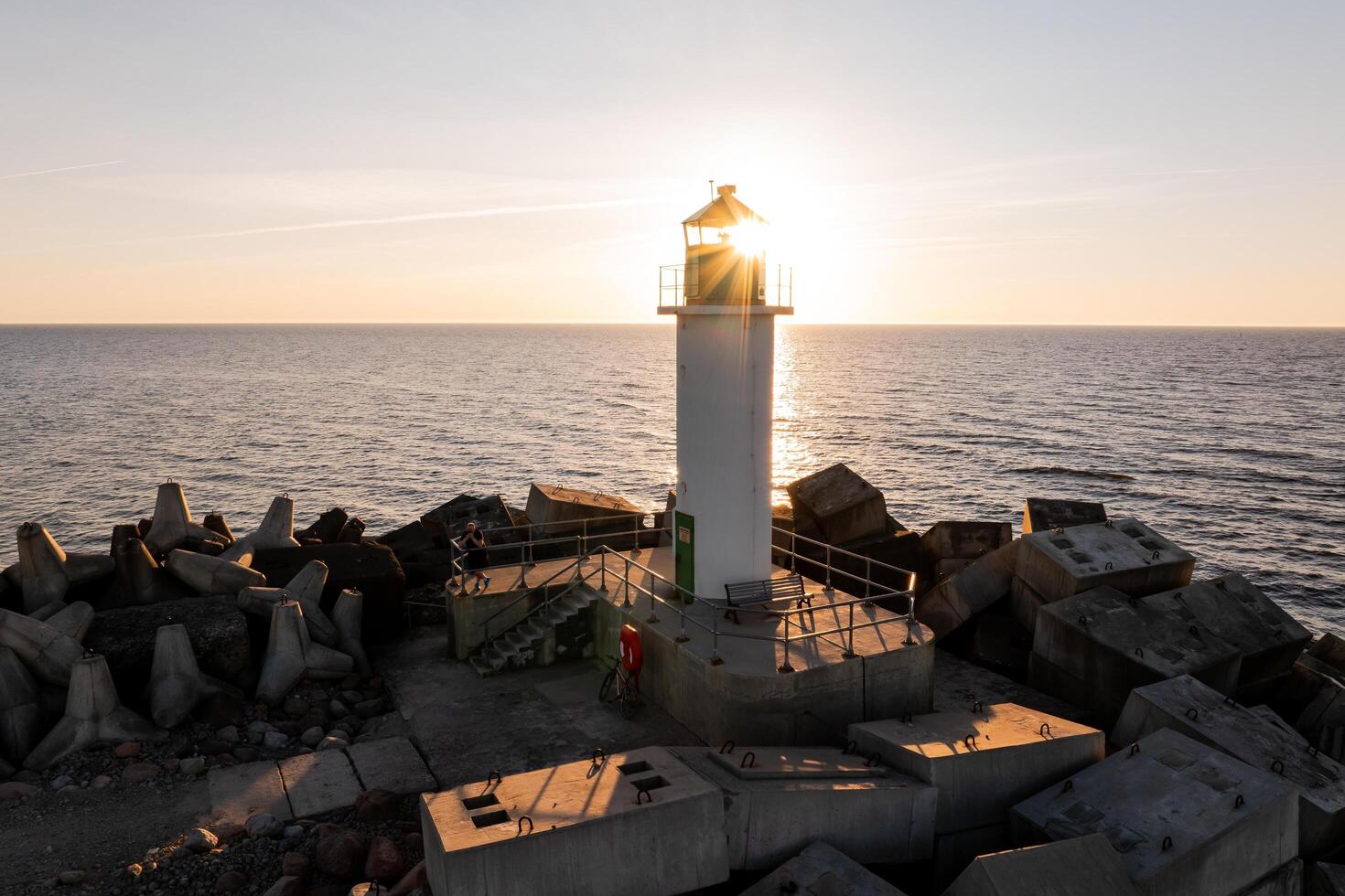 Riga, Latvia, 2024 - Lighthouse Silhouette on Breakwater at Sunset with Ocean Horizon photo