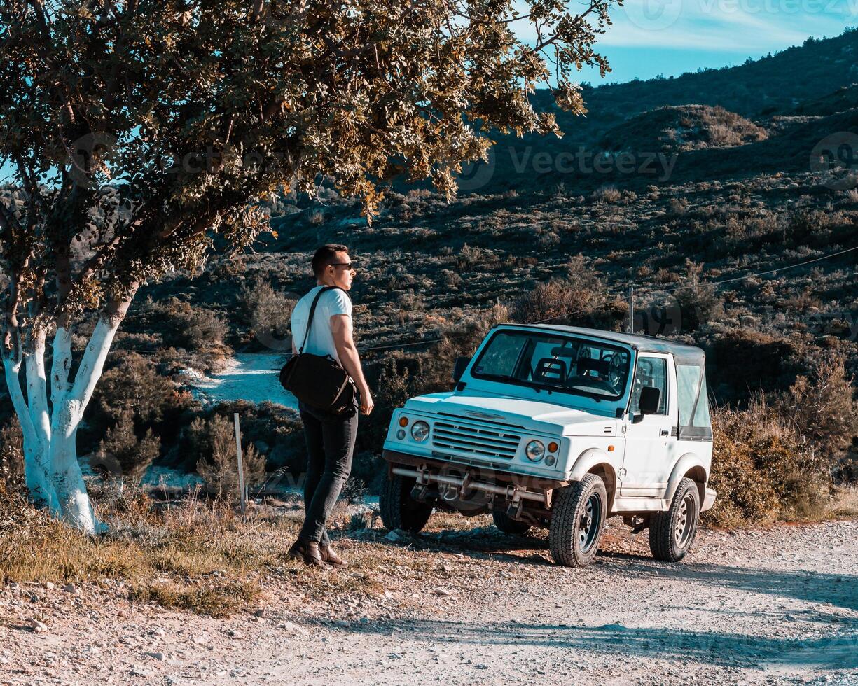 Man Standing by White Off Road Vehicle on Dirt Path in Rugged Terrain photo