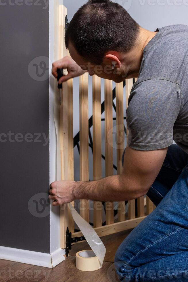 Person Installing Wooden Safety Gate in Two Tone Painted Room photo