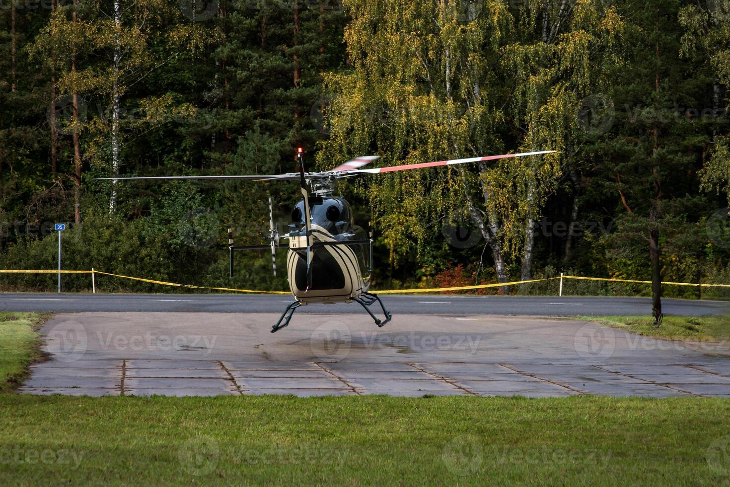 Helicopter Landing on Paved Helipad Surrounded by Forested Area photo