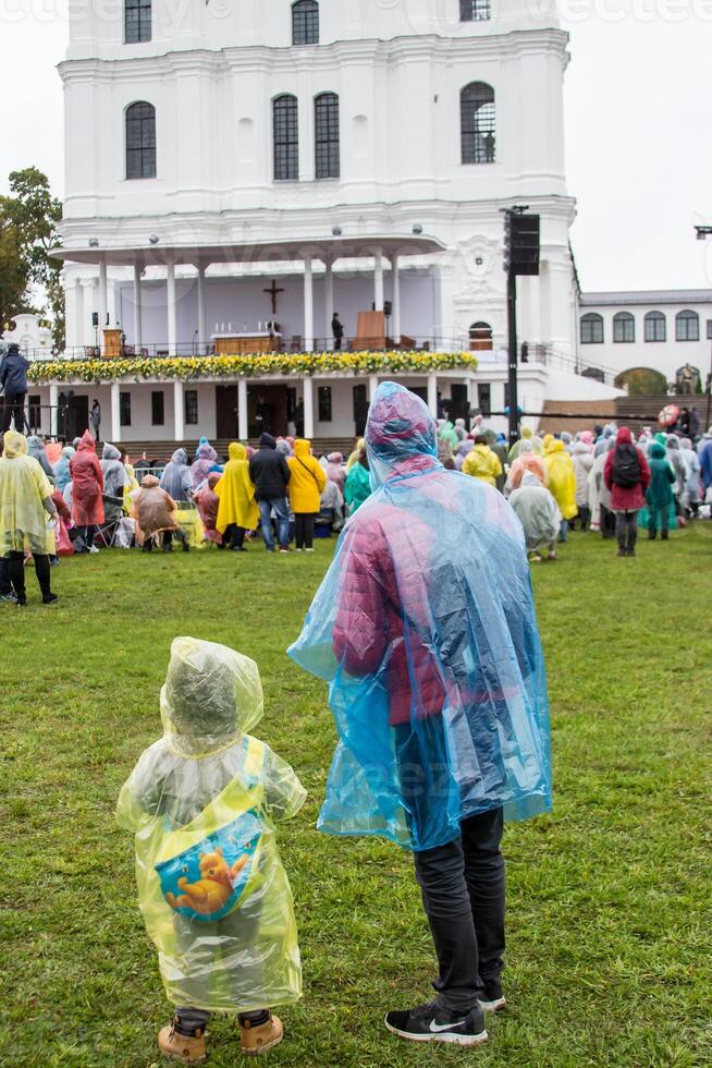 Crowd in Rain Ponchos Gathered at White Church with Classical Design photo