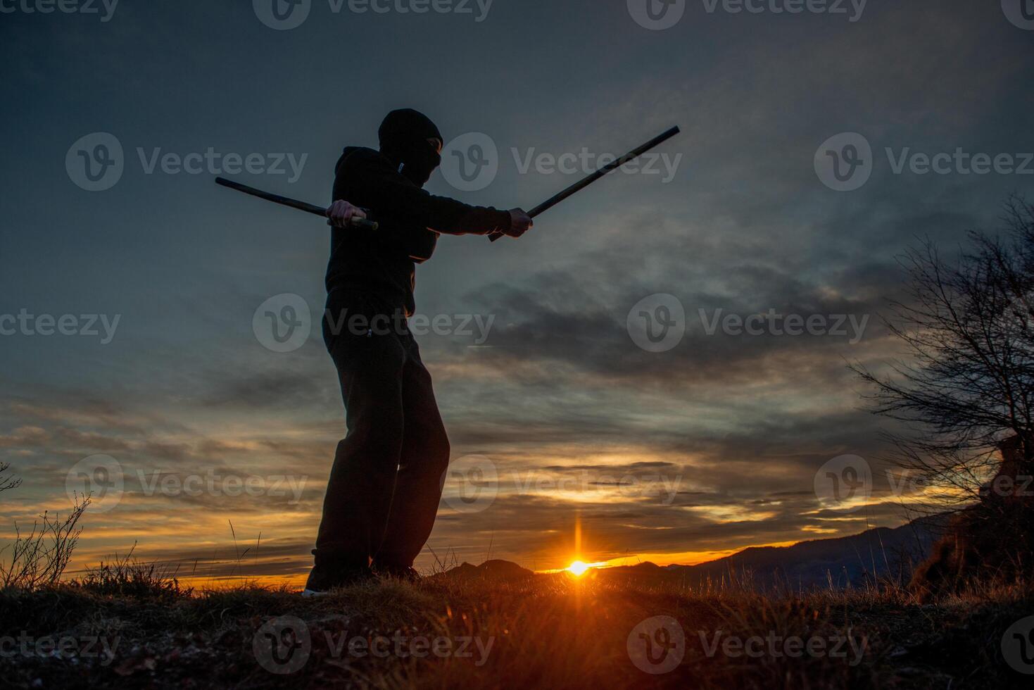 Stick Weapons Combat TrainingTraining with poles at sunset on the top of the mountain photo