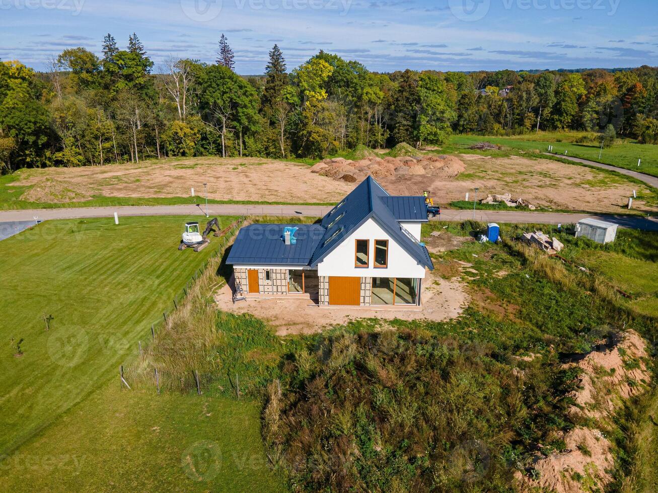 Modern House with Blue Metal Roof in Rural Area with Forest Backdrop photo
