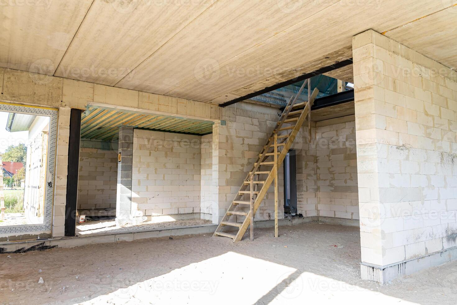 Interior of Unfinished Building with Concrete Walls and Wooden Ladder photo