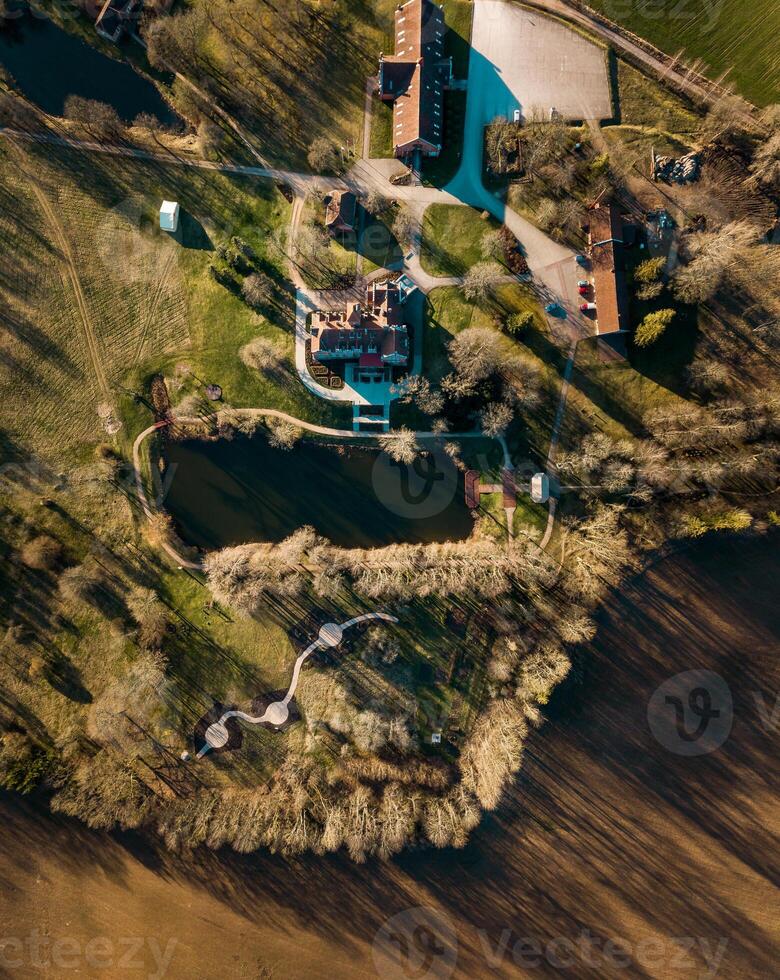 Aerial View of Countryside Estate with Red Roof and Surrounding Fields photo