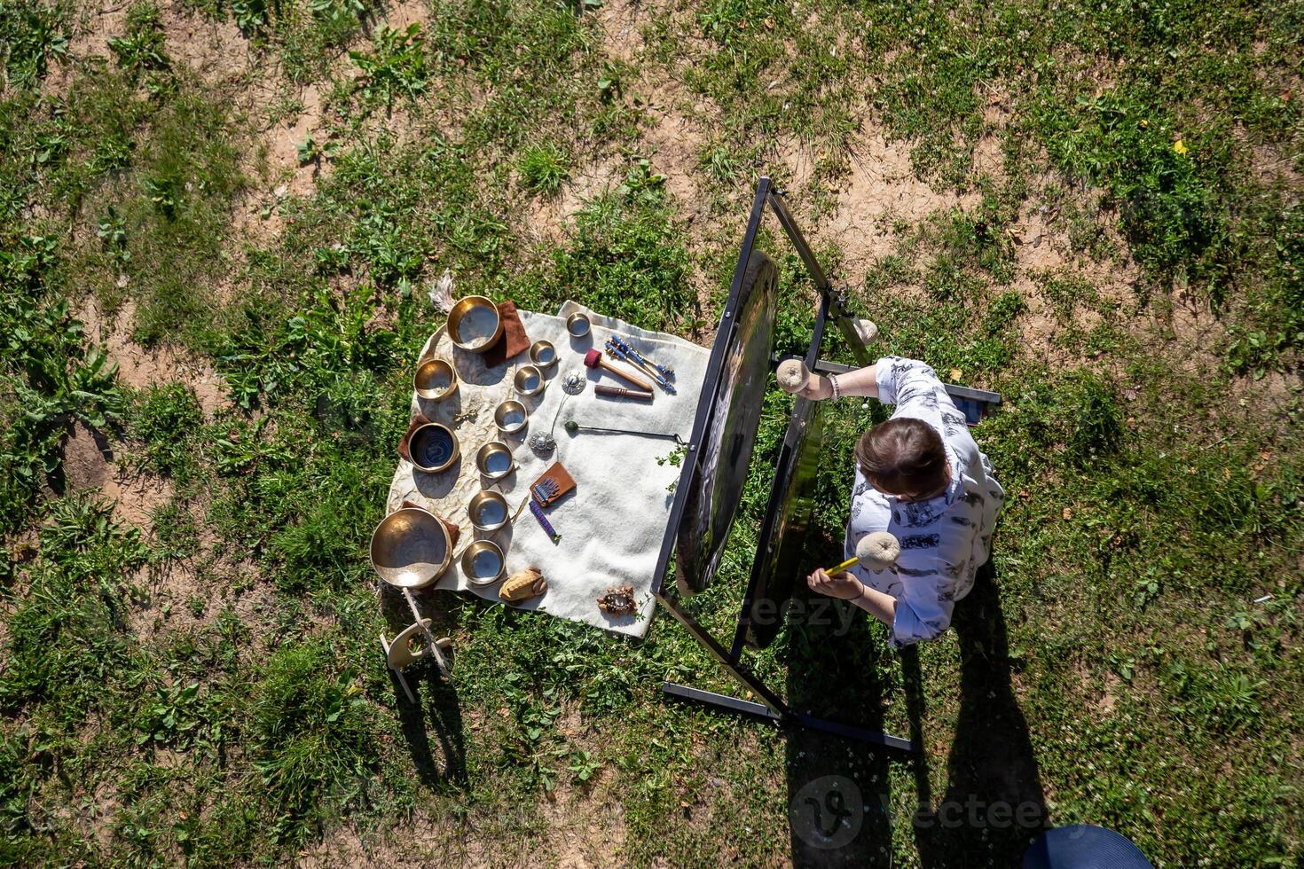 Aerial View of Person Playing Gong with Singing Bowls on Grass photo