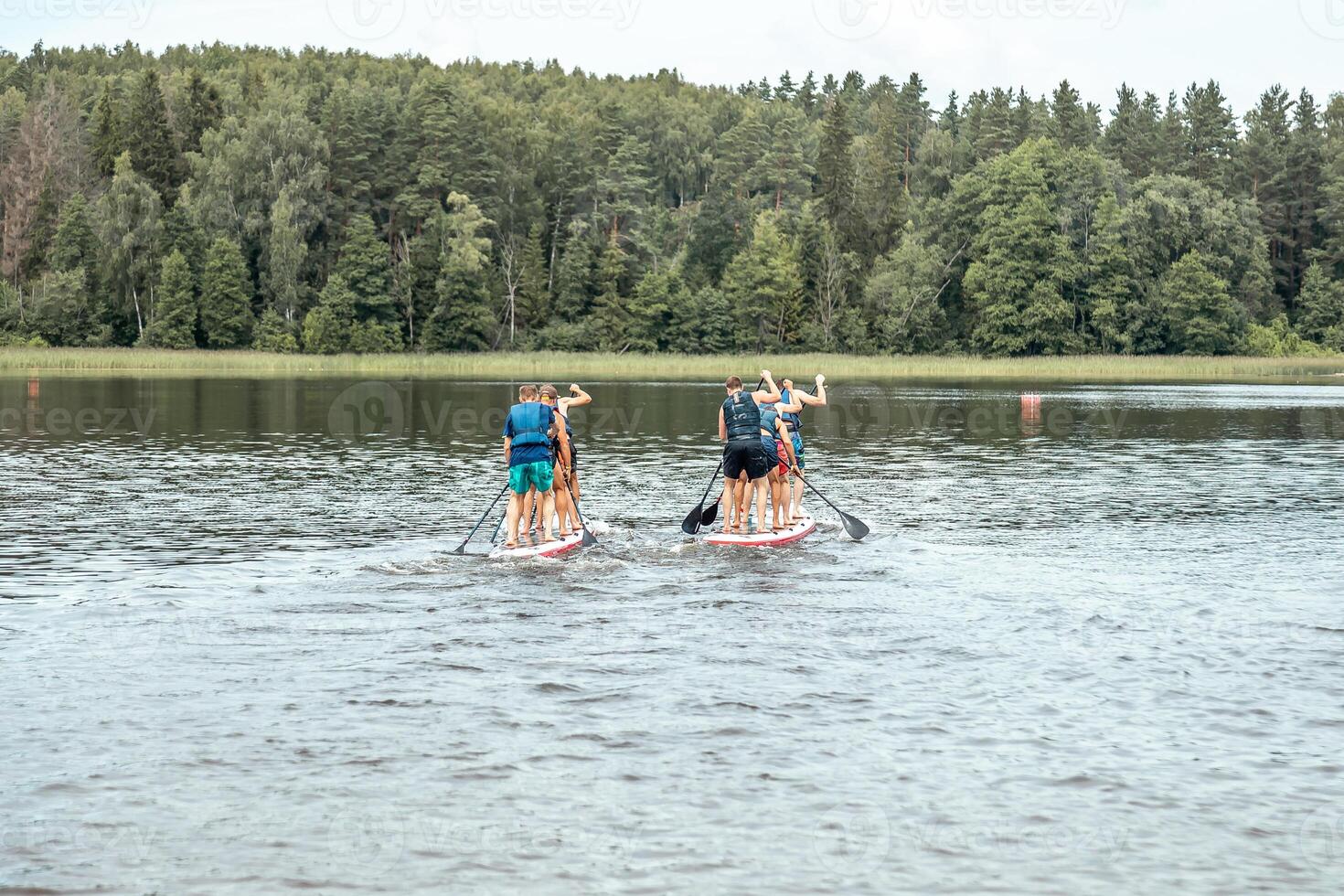 Paddleboarders on a Calm Lake Surrounded by Dense Green Forest photo