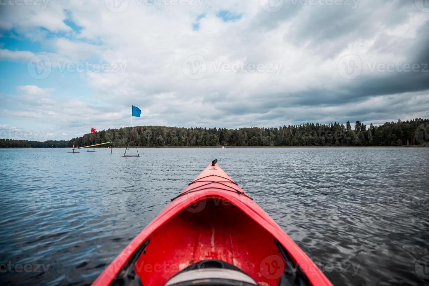 Red Kayak on Calm Lake with Forested Shoreline and Floating Platforms photo
