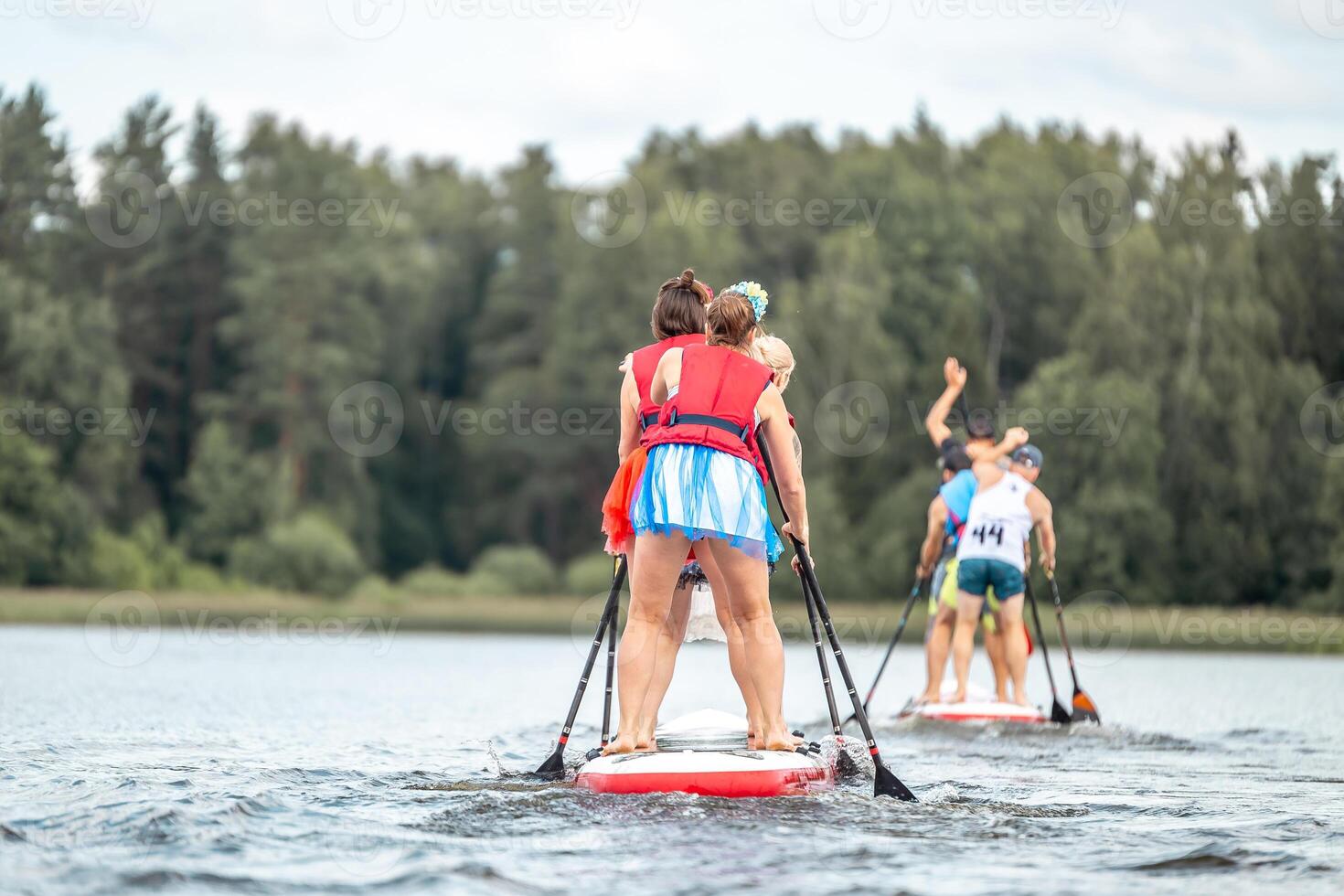 Group Paddleboarding on Calm Water Surrounded by Forest Trees photo