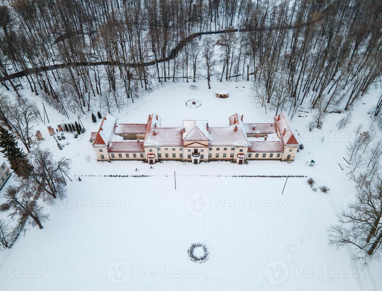 Aerial View of Snow Covered Estate with Red Roof and Forest Border photo