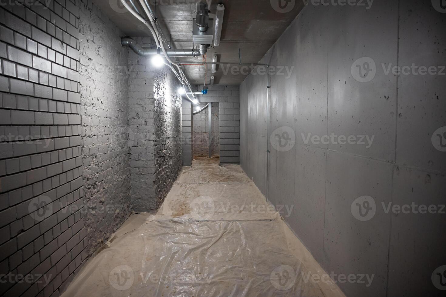 Narrow Corridor with Exposed Brickwork and Visible Ceiling Pipes photo
