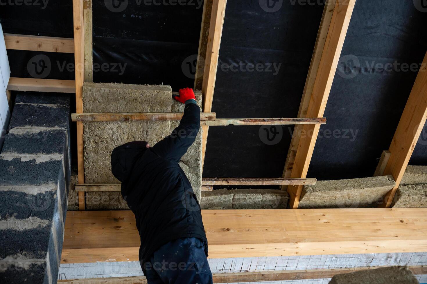 Worker Installing Insulation in Partially Constructed Building Frame photo