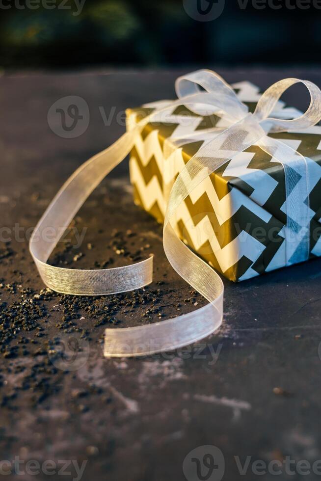 Gift Box with Zigzag Pattern and Translucent Ribbon on Dark Surface photo