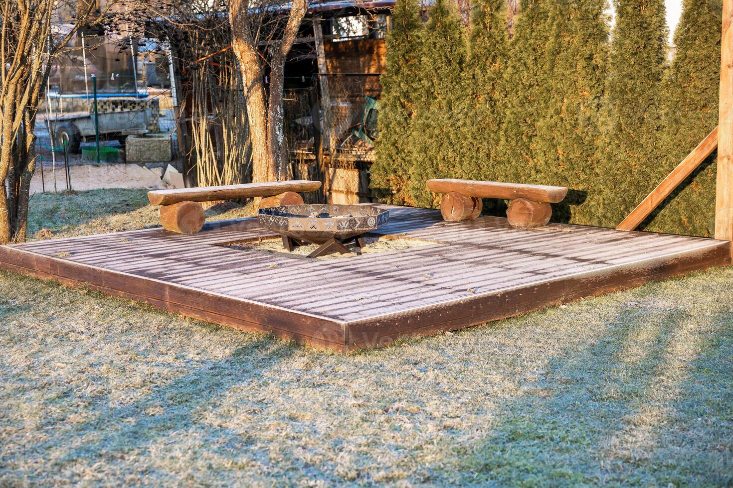 Wooden Deck with Fire Pit and Benches Amid Frosted Evergreen Trees photo