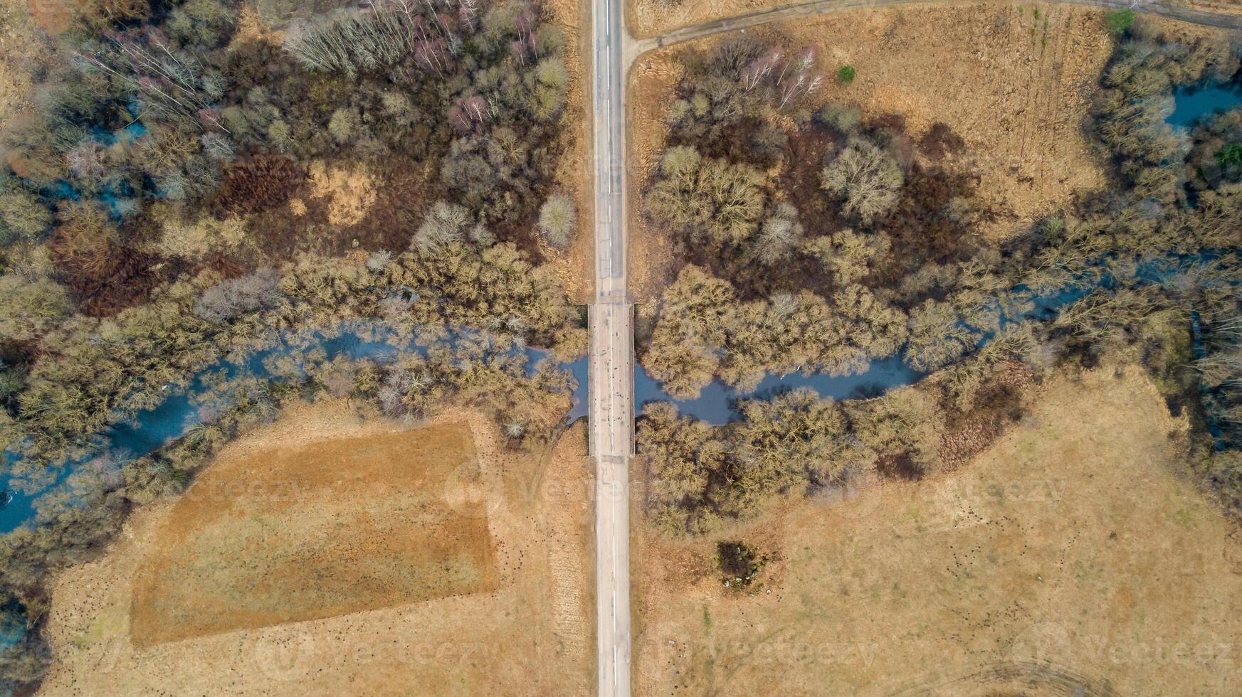 Aerial View of Narrow Bridge Over Winding River and Dry Fields photo