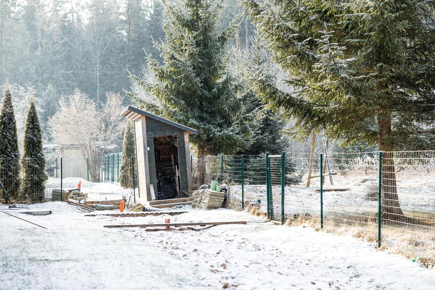 Rustic Wooden Shed in Snow Covered Area Surrounded by Evergreen Trees photo