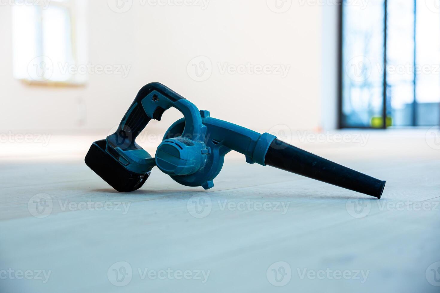 Blue Handheld Cordless Blower on Light Wooden Floor in Minimalist Room photo