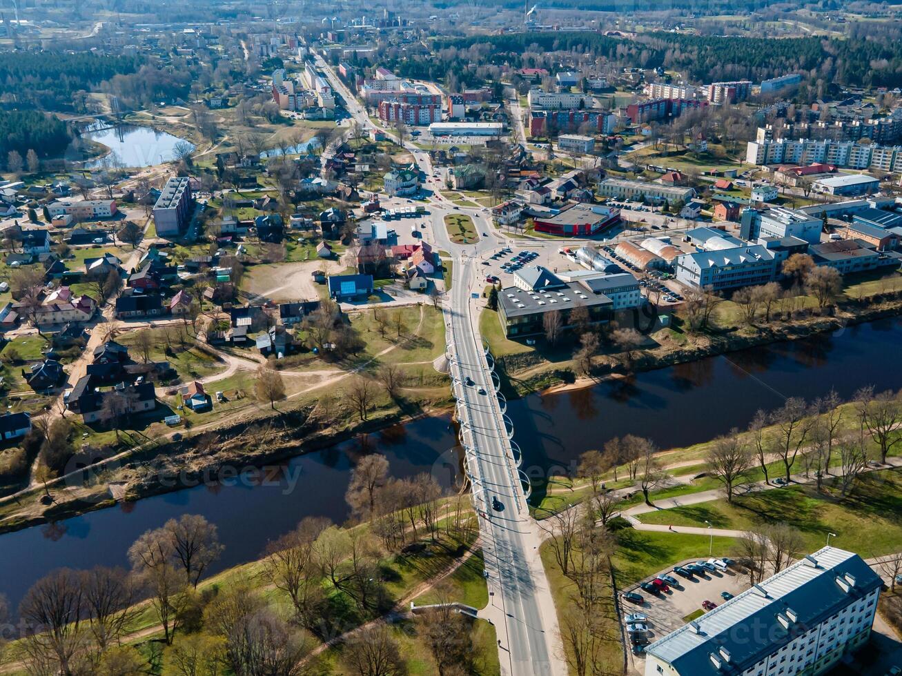 Aerial View of a Small Town with Bridge and Surrounding Green Spaces photo