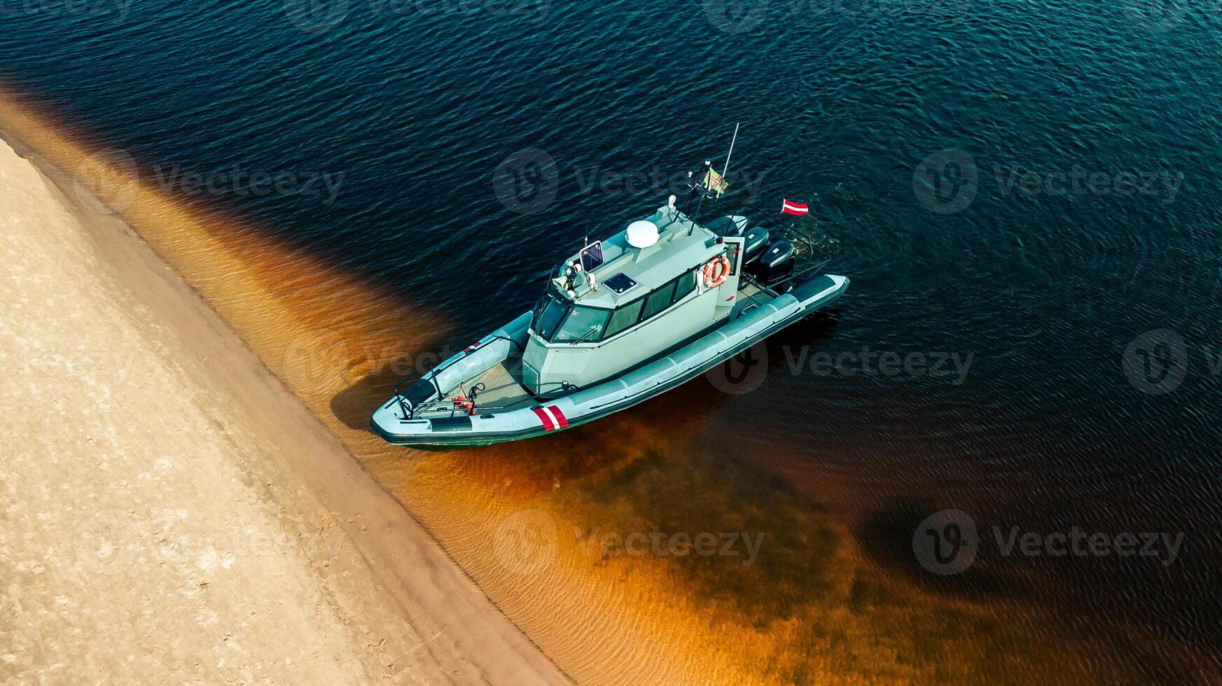 Border Guard Patrol Boat Docked Along Sandy Shoreline photo