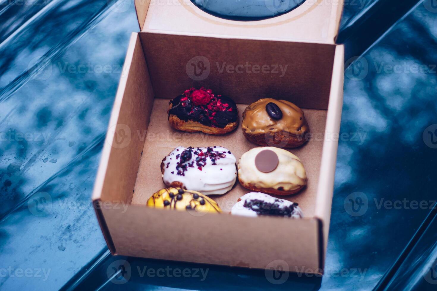 Cardboard Box with Five Decorated Pastries on Reflective Surface photo
