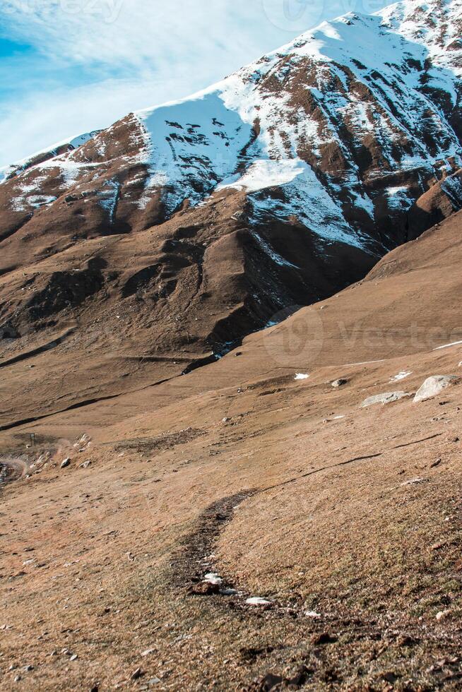 Snow Capped Mountain with Dry Terrain and Winding Path in Georgia photo