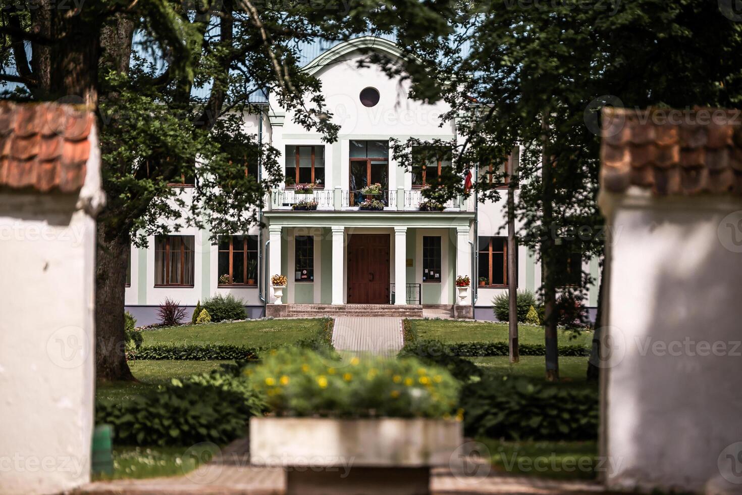 White Two Story Building with Columns and Garden Pathways photo