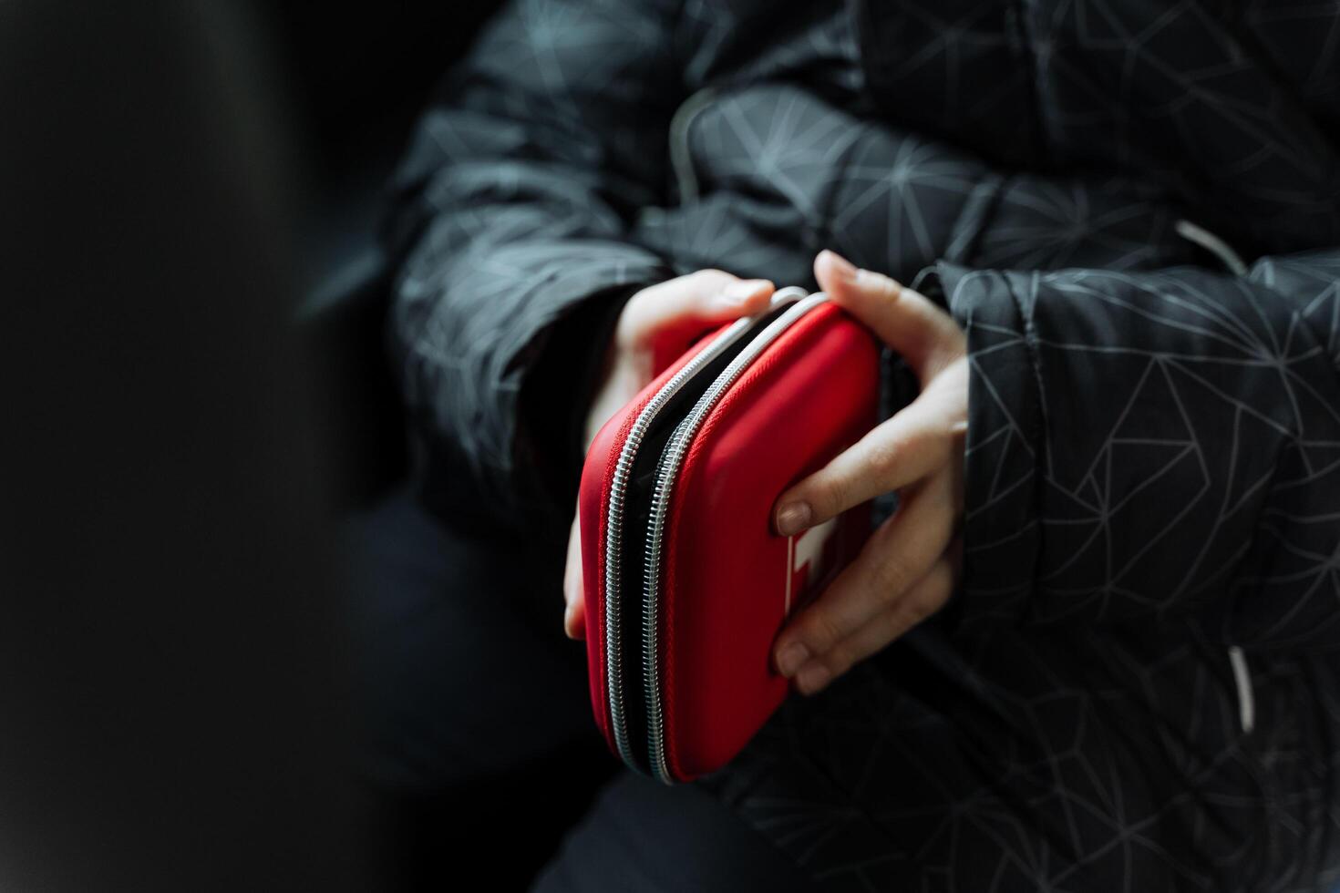 A person is confidently holding a stylish red case in their hands, likely made of leather, which may contain various gadgets or essentials for their everyday carry needs photo
