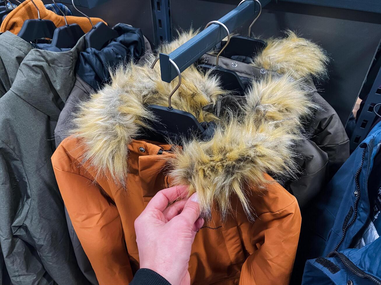 A shopper is currently contemplating the purchase of a warm and stylish fur hooded jacket that is perfect for keeping cozy and is also quite trendy during the cold winter season photo