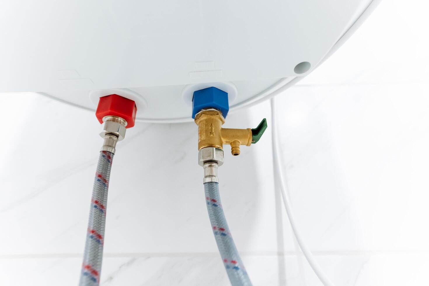 This is a closeup image of a water heater that features two hoses securely attached to it, showcasing the intricate details and components necessary for its operation and functionality photo