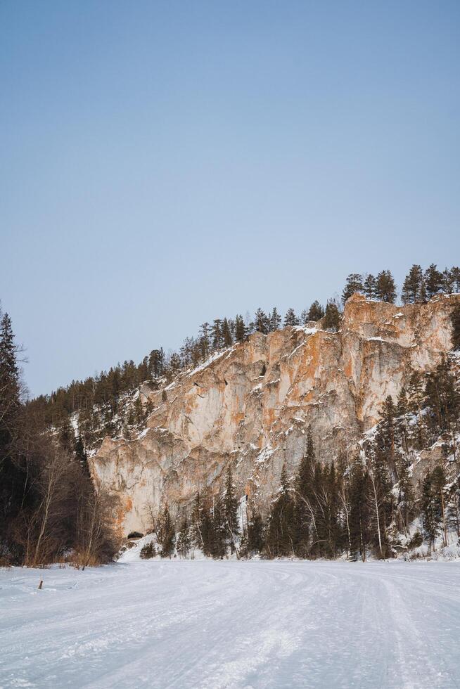 A beautiful snowy landscape featuring a majestic mountain towering in the background, while an array of trees stands prominently in the foreground, highlighting the serene winter scene photo