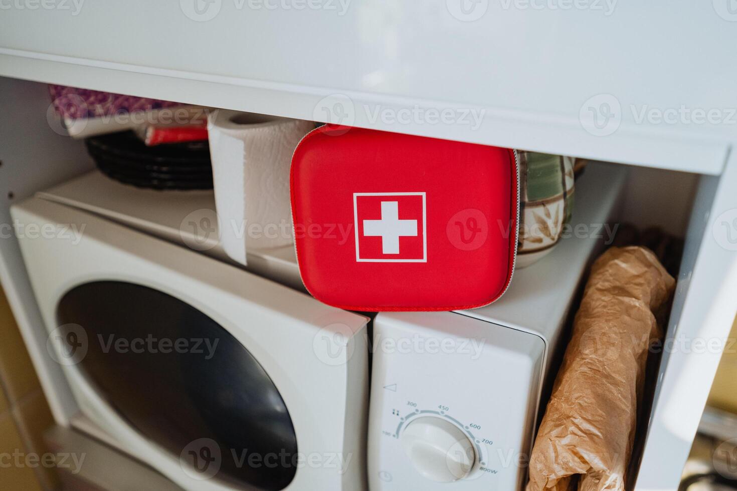 A red First Aid Kit positioned conveniently on top of the washing machine, easily accessible for home storage in case of any emergency health situations that may arise photo
