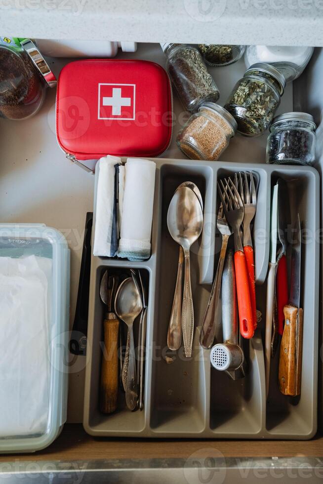 This drawer in the kitchen is meticulously organized to hold cutlery, spices, and a first aid kit, ensuring efficiency and neatness for all your cooking and dining needs photo