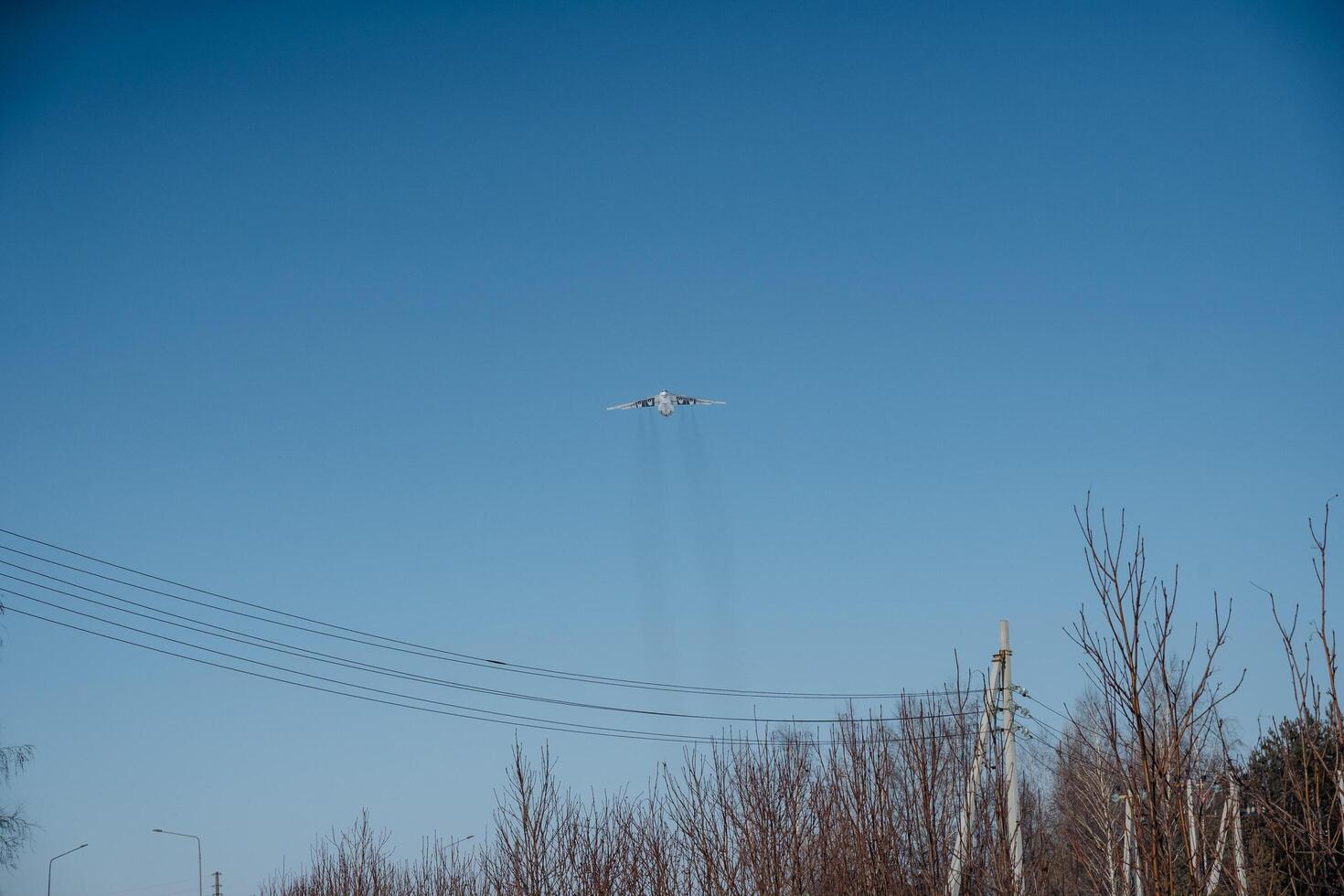 An airplane soars through the blue sky above a green forest, contrasting aviation technology with the tranquil beauty of nature as it glides effortlessly on its heavenly journey photo