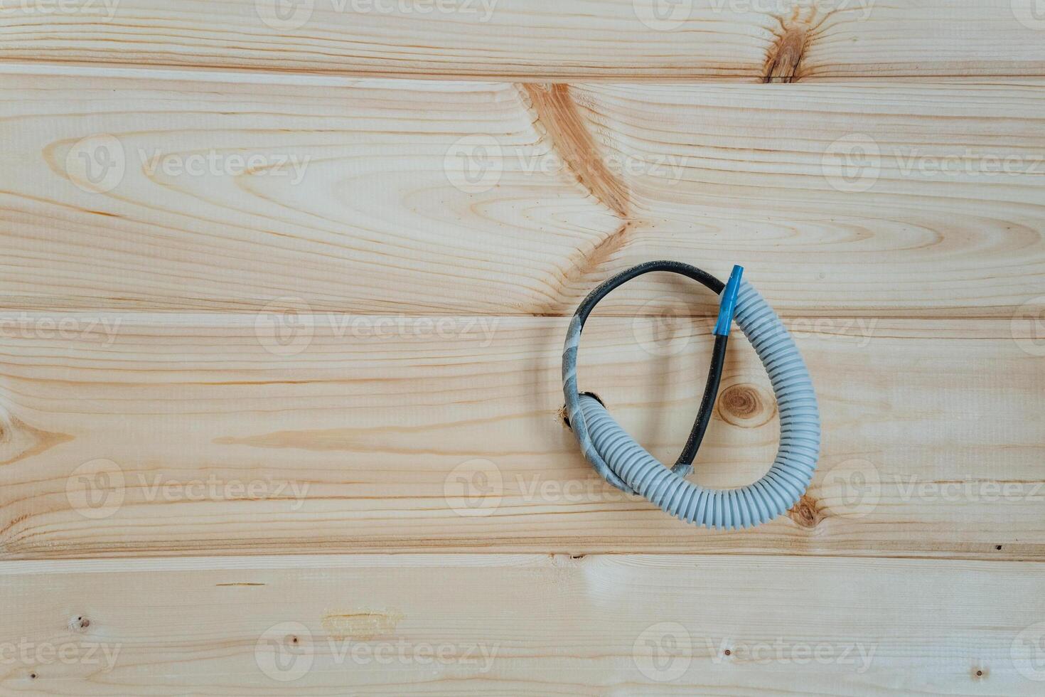 A hose has been properly connected to a wire that runs along a wooden wall, showcasing the interaction between the two elements in this unique setup for functional purpose photo