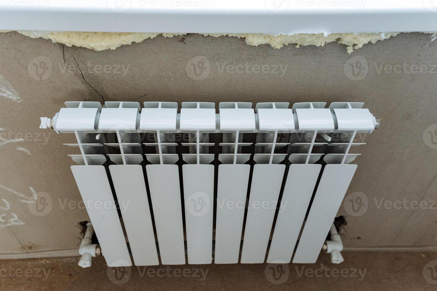 A sleek and modern white radiator has been installed on the wall, but the visible damage above it requires urgent repair in order to ensure both safety and aesthetic appeal photo