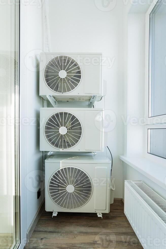 In a room, three air conditioning units are carefully stacked one on top of the other, optimizing the limited space available. This setup is useful for cooling the environment efficiently photo