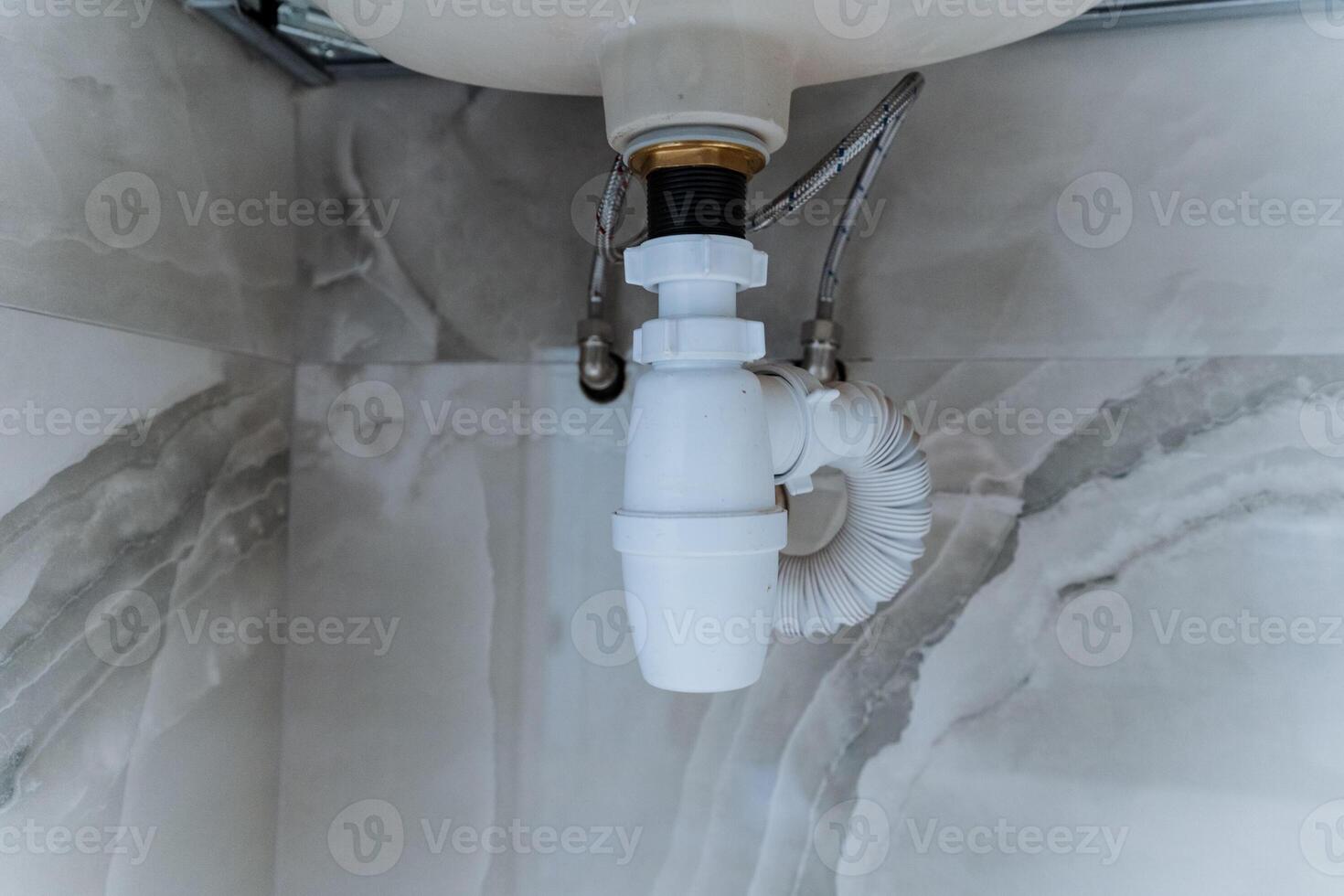 This is a closeup photograph of a sink drain located in a bathroom, showcasing the intricate details and design of the plumbing fixture and its connection to the household drainage system photo