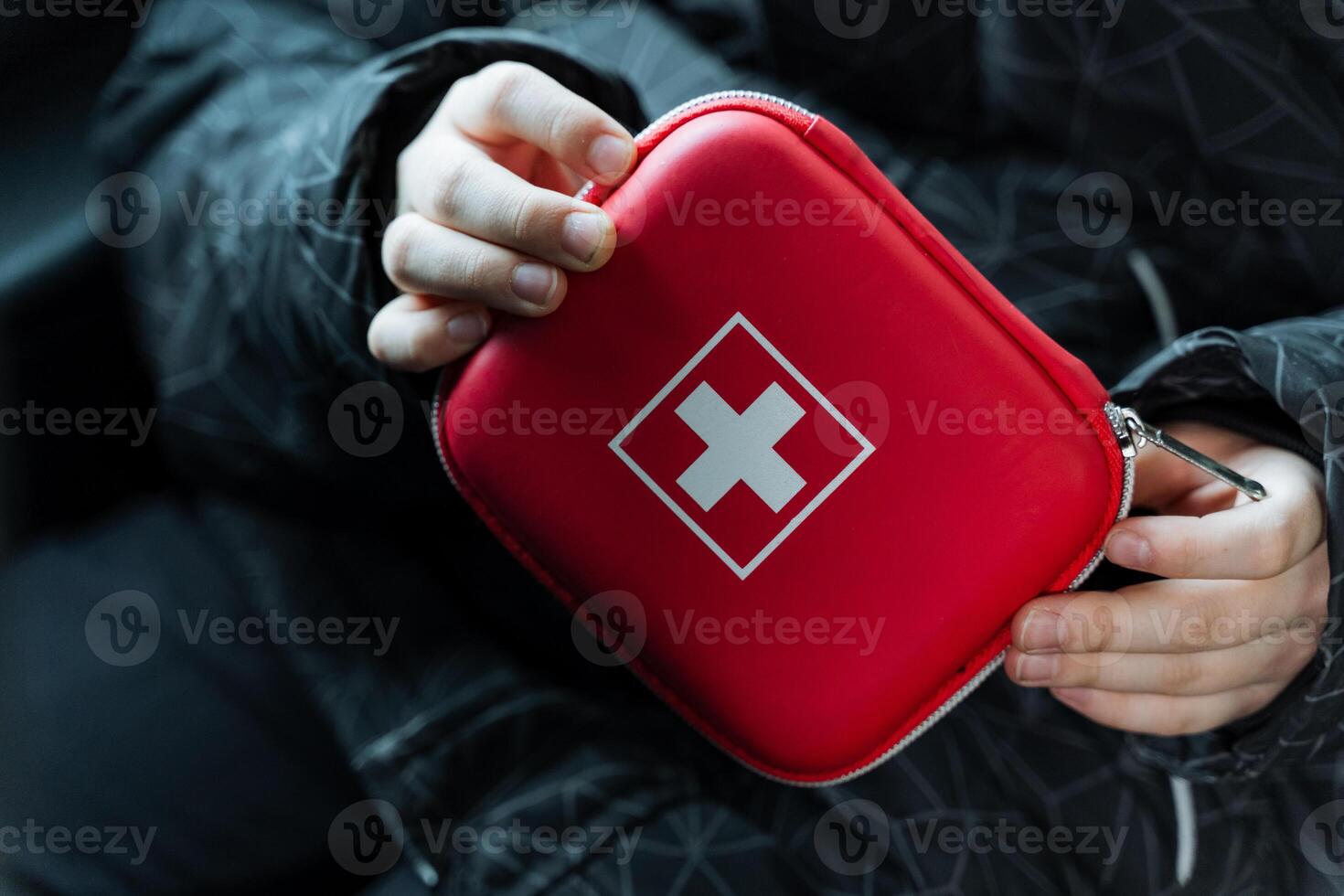 A person is confidently holding a bright red first aid kit, prominently featuring a white cross symbol, which highlights its vital role as an essential resource in medical emergencies photo