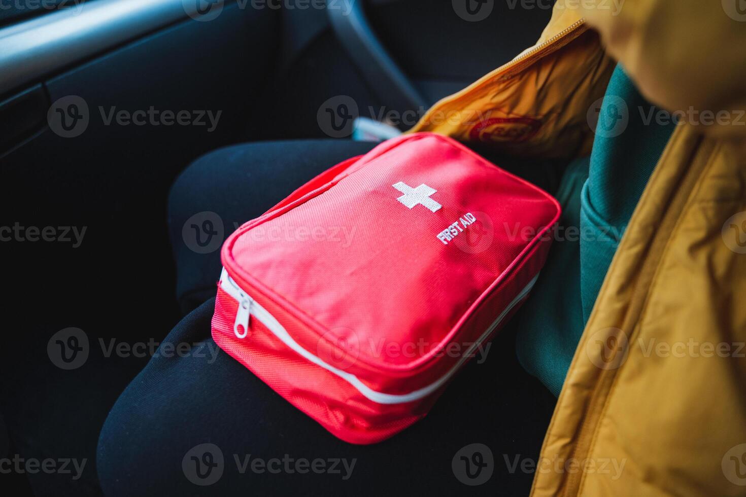A person is comfortably sitting in a car with a first aid kit resting in their lap, ready for any potential accidents or emergencies that might occur during their journey photo