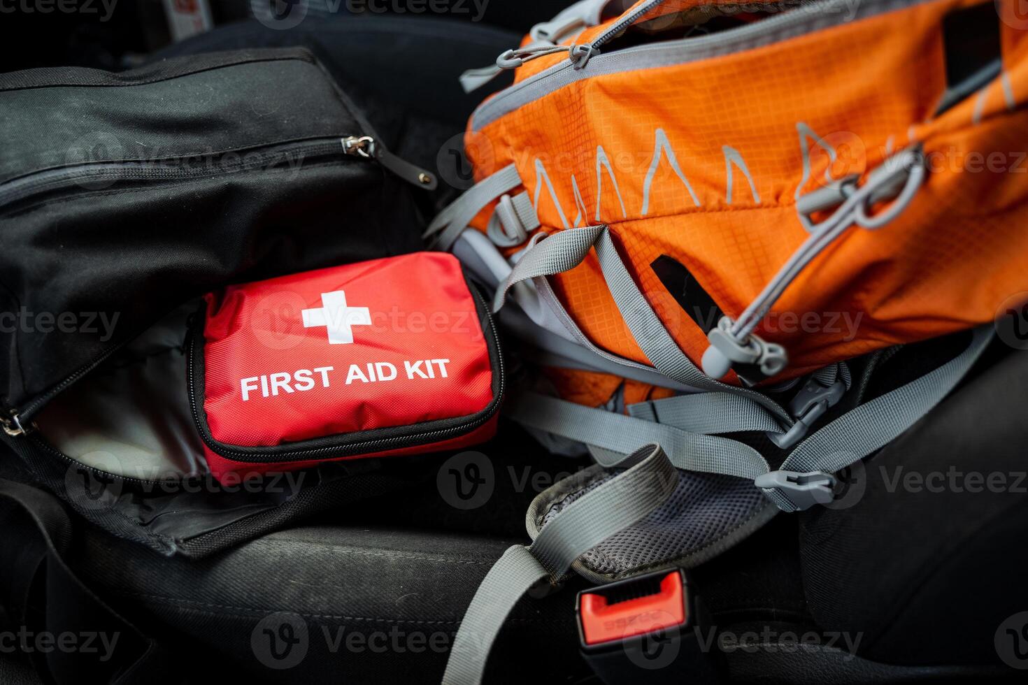 A stylish orange backpack sits next to a wellorganized first aid kit, essential for emergencies. This combo is a musthave for explorers and commuters, ensuring preparedness photo