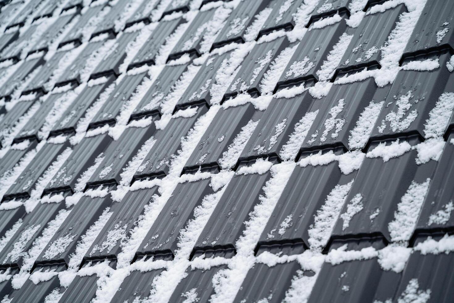 This closeup photo captures a beautiful snowcovered roof, highlighting the enchanting allure of winter against the grey and silver materials of the surrounding structure