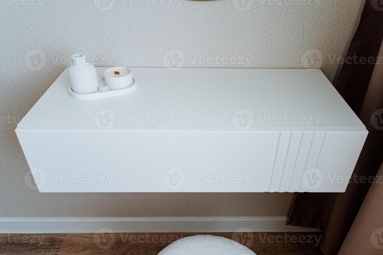 A beautifully arranged white shelf features an elegant vase alongside a lit candle, which is gracefully placed on it, adding a delightful touch of style and warmth to the decor of any room photo